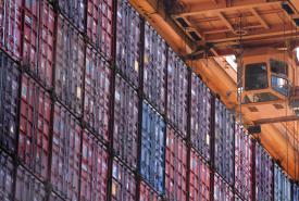 Crane operator next to stack of containers.